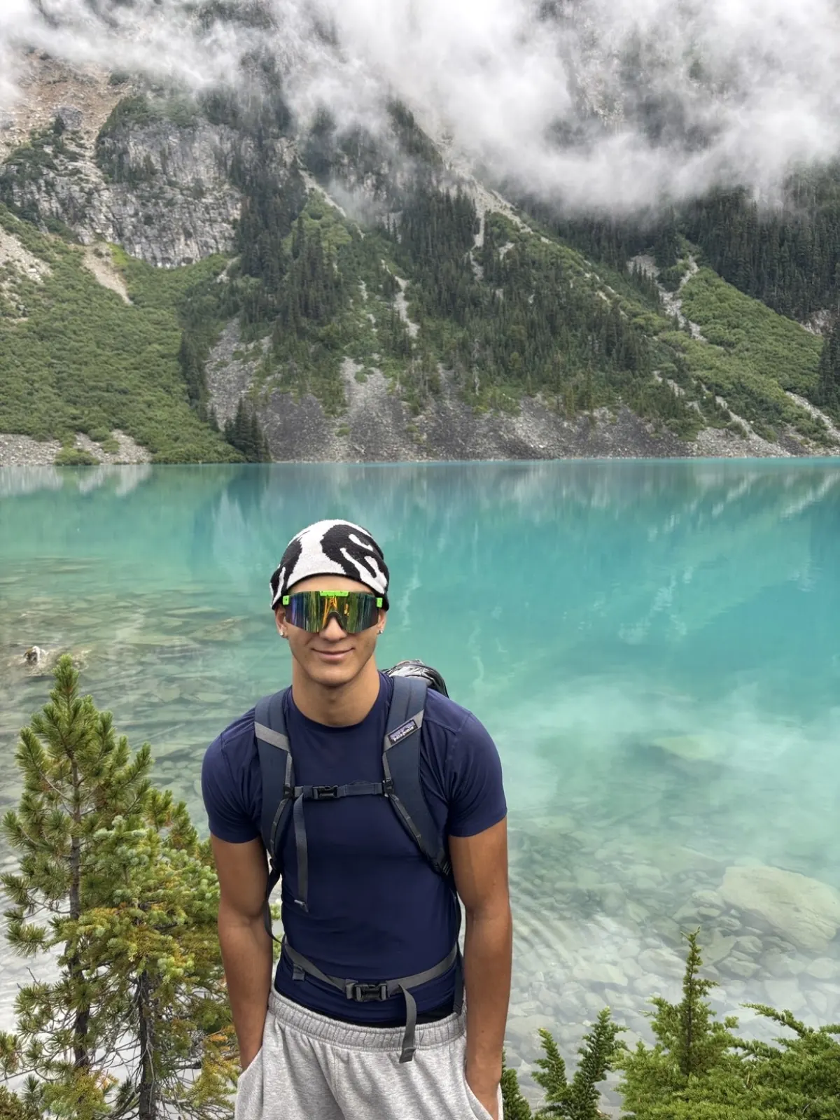 Mani on a hike in front of a turquoise mountain lake